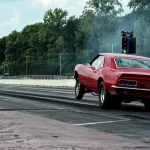 A drag racer practices reaction time in a garage with a light timer and stopwatch.