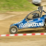 Beginner autocross car parked by cones in a paddock with a driver checking tires
